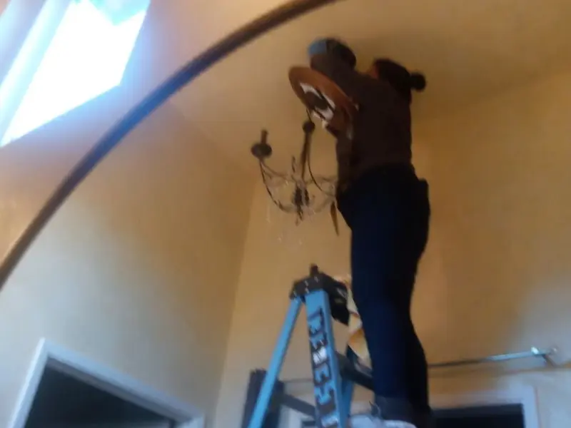Electrician installing a chandelier in a Union Park residence